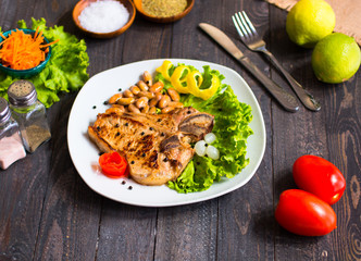 Pork steak homemade cooking with spices leaves lettuce on wooden cutting board, and a dish,