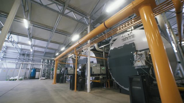 Three large gas boilers in an automated boiler house. Interior industrial with a lot of piping, pumps and valves. Modern boiler room equipment for heating system. Pipelines, water pump