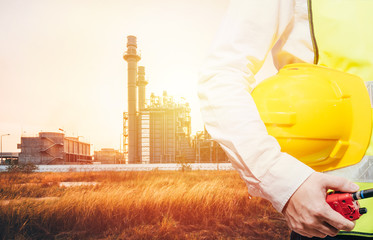 engineering man standing with white safety helmet against oil refinery in petrochemical Aerial view oil refinery night during twilight,Industrial zone,Energy power station background.