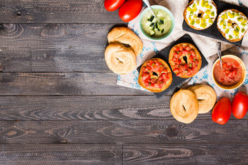 Fototapeta na wymiar Italian bruschetta with cheese, tomato sauce, cucumber sauce, and herbs, on a wooden background.