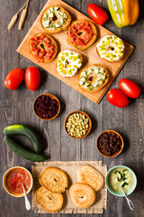 Italian bruschetta with cheese, tomato sauce, cucumber sauce, and herbs, on a wooden background.