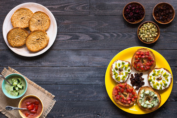 Italian bruschetta with cheese, tomato sauce, cucumber sauce, and herbs, on a wooden background.