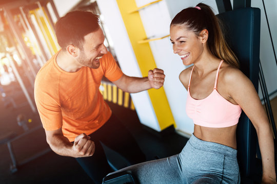 Young attractive woman doing exercises in gym with personal trainer