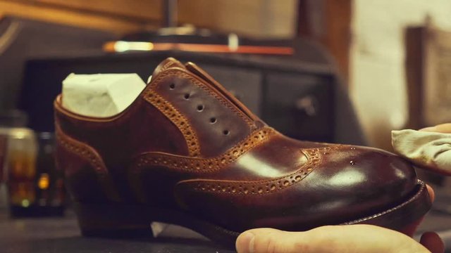 Close up of bootmaker hands polishing a leather shoe at workshop