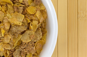 Top close view of multigrain breakfast cereal in a white bowl atop a wood place mat.