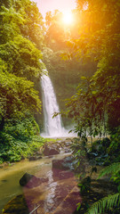 Fototapeta na wymiar Sunlight over Jungle Nungnung waterfall, Bali, Indonesia
