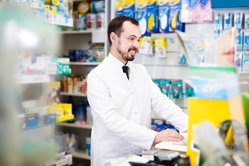 Pharmacist browsing rows of pills in drugstore