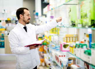 Male pharmacist checking assortment of drugs