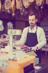 Fototapeta premium male seller weighing piece of meat in butcher’s shop