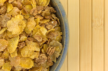 Top close view of multigrain breakfast cereal in an old bowl atop a wood place mat.