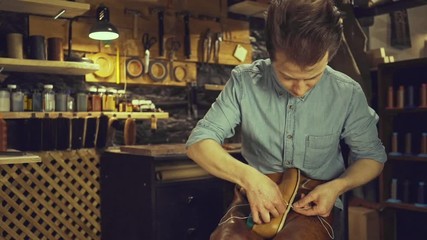 Young concentrated cobbler man repairing a shoe at his workshop