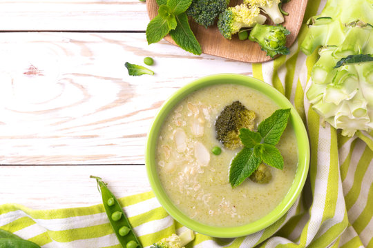 Broccoli and green peas puree soup decorated with mint