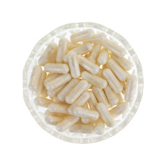 Top view of a glass bowl filled with nicotinamide riboside capsules isolated on a white background.