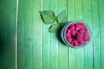 Fresh ripe raspberries on green wooden boards.