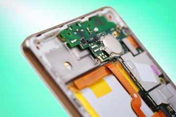 Smartphone back cover removed as part of disassembly process, focus on circuit board.