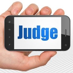 Law concept: Hand Holding Smartphone with Judge on display