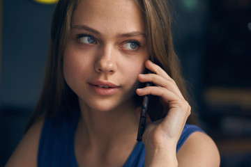 Fototapeta premium Young beautiful woman calls by phone in cafe