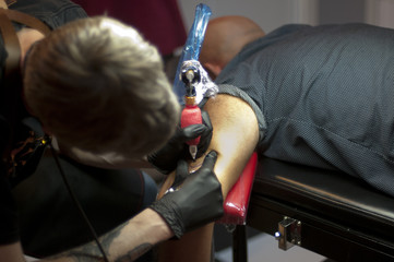 homme se fait tatouer le bras tatoueur