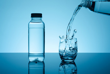 Bottle with creative splashing water in the glass