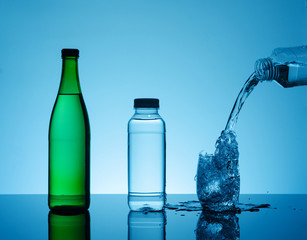 Bottle with creative splashing water in the glass