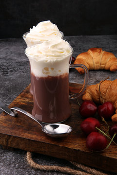 Iced coffee with whipped cream in tall glass and fresh croissant