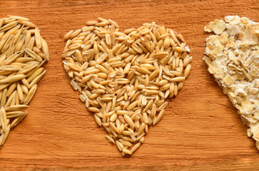 Three hearts from oat grains close-up on a wooden background