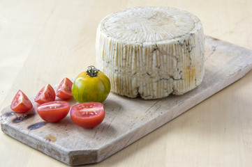 Pecorino cheese on wooden table with red and green tomatoes