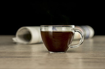 Close up shot of a glass cup of coffee and newspaper