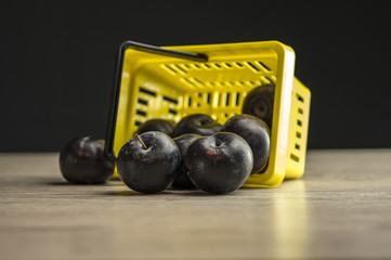 Close up shot of a yellow supermarket basket filled with plums