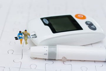 Miniature people sitting on a glucose meter health care concept.