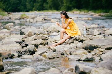 Travel in mountains. River with stones on shore. Heat temptation. Thirst suffer. Young girl drinking water. Satisfaction of wish.  Eyes closed in peace and harmony.  Rest in pleasure.  Tired under sun