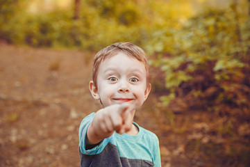 Joyful and surprised boy pointing at something. Curious kid smiles happily after seeing something amazing. Closeup