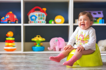 Smiling baby girl, sitting on chamber pot .