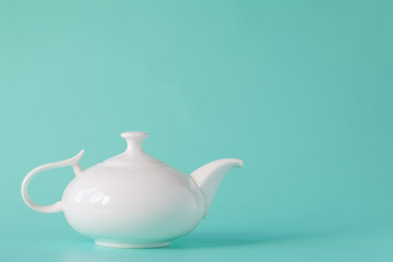 White teapot isolated on aquamarine background