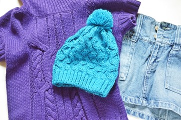 Flat lay women's clothings/ Autumn and winter casual outfit. Purple woolen sweater, a blue knitted hat and a denim skirt
