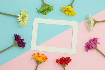 Empty frame and flowers flat lay on blue and pink pastel background with copy space. Soft effect filter. Minimal concept.