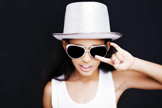 Little girl rocker with sunglasses and hat on a black background