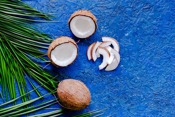 Appetizing coconut and palm branch on blue table background top view copyspace