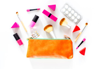 Beauty bag with cosmetics, contraceptives and pills on white table background top view