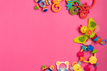 Children's rattle from plastic on a pink background. Top view