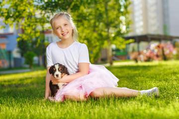 Little girl with a berner sennenhund puppy, outdoor, summer