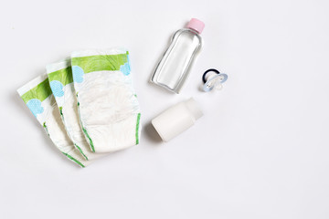 Babies goods diaper, baby powder, cream, shampoo, oil on white background with copy space. Top view...