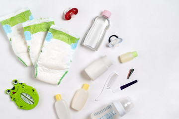 Babies goods diaper, baby powder, cream, shampoo, oil on white background with copy space. Top view...