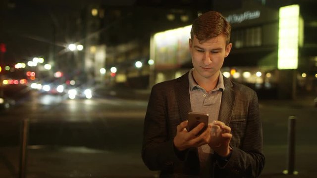 Young man is thumbing a text message on a street