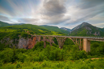 Fototapeta na wymiar Durdevica arched Tara Bridge over green Tara Canyon at evening time - Montenegro