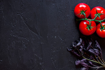 Cook workplace. Tomato and basil on black table background top view copyspace