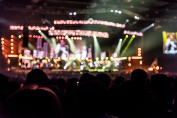 silhouettes of concert crowd in front of bright stage lights 