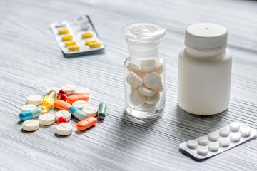 Vitamins and supplements. Pills and pill bottle on grey wooden table background