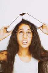 Adorable girl with eyeglasses and book on the head on white background