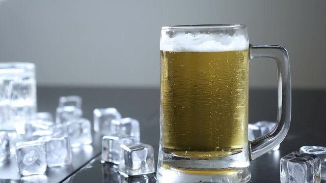 Beer in glass on a wooden table, ice cube background.
